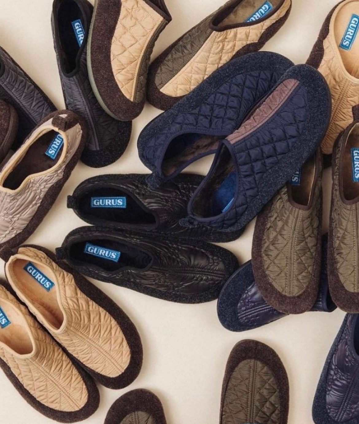 Gurus quilted house shoes in tan, navy, olive and black with brown felt trims, scattered on a pale ground.
