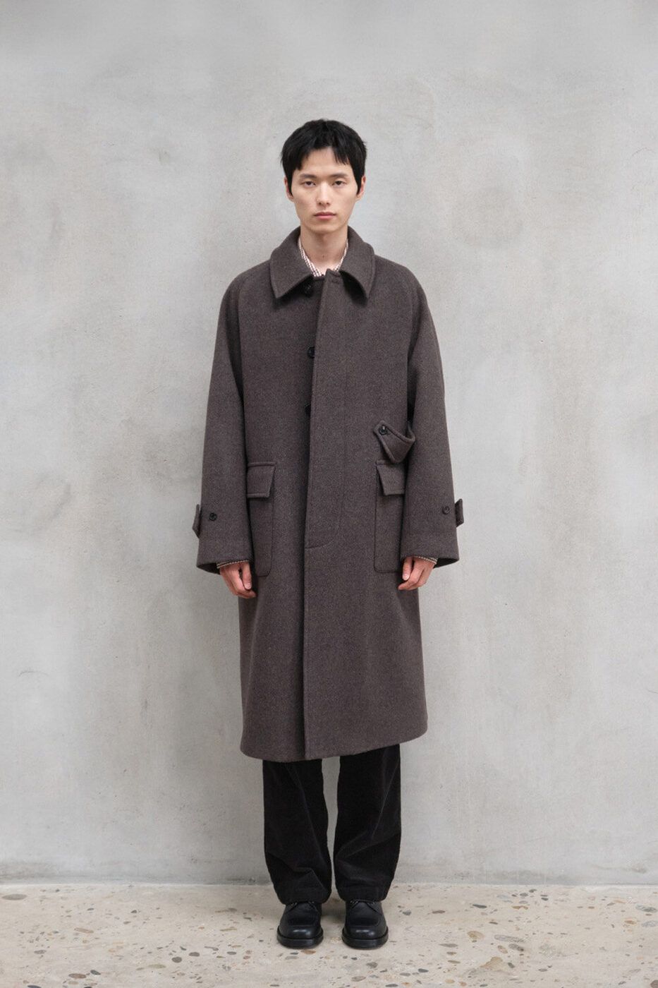 The Horlisun Winterport wool coat in olive, worn over dark trousers.