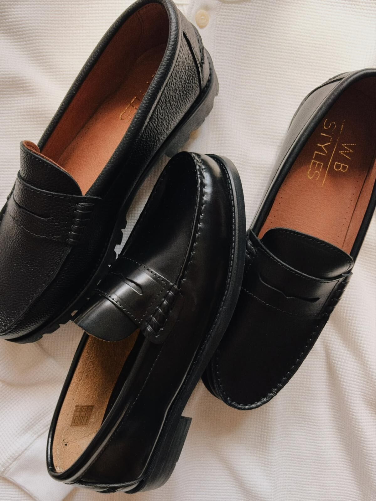 Black WB Styles loafers on chunky soles, laid on a white knit.