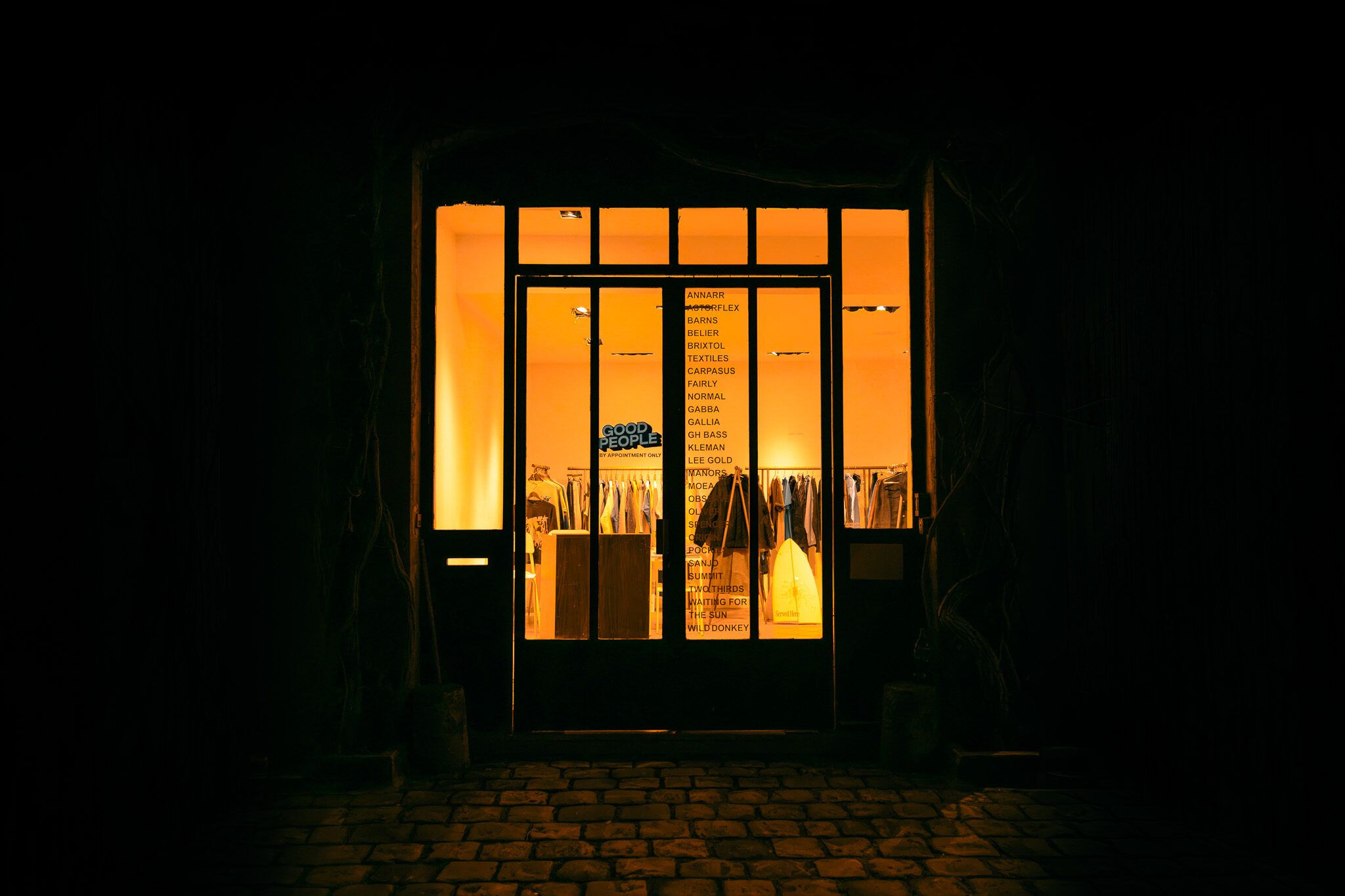 The Good People showroom at night, the door lit from inside.
