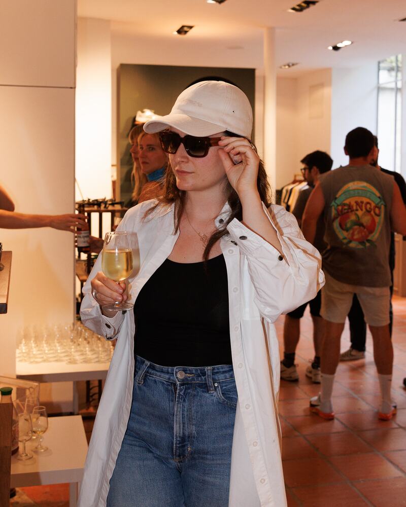 A visitor in a white cap and sunglasses with a glass of wine.