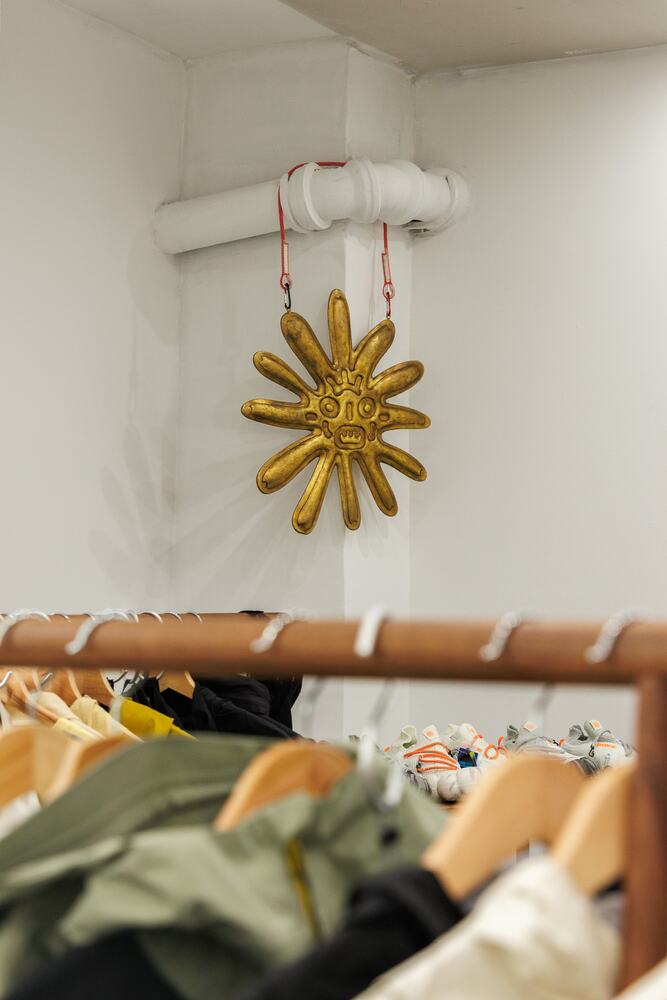 A gold sun ornament hanging above a rail of clothes.