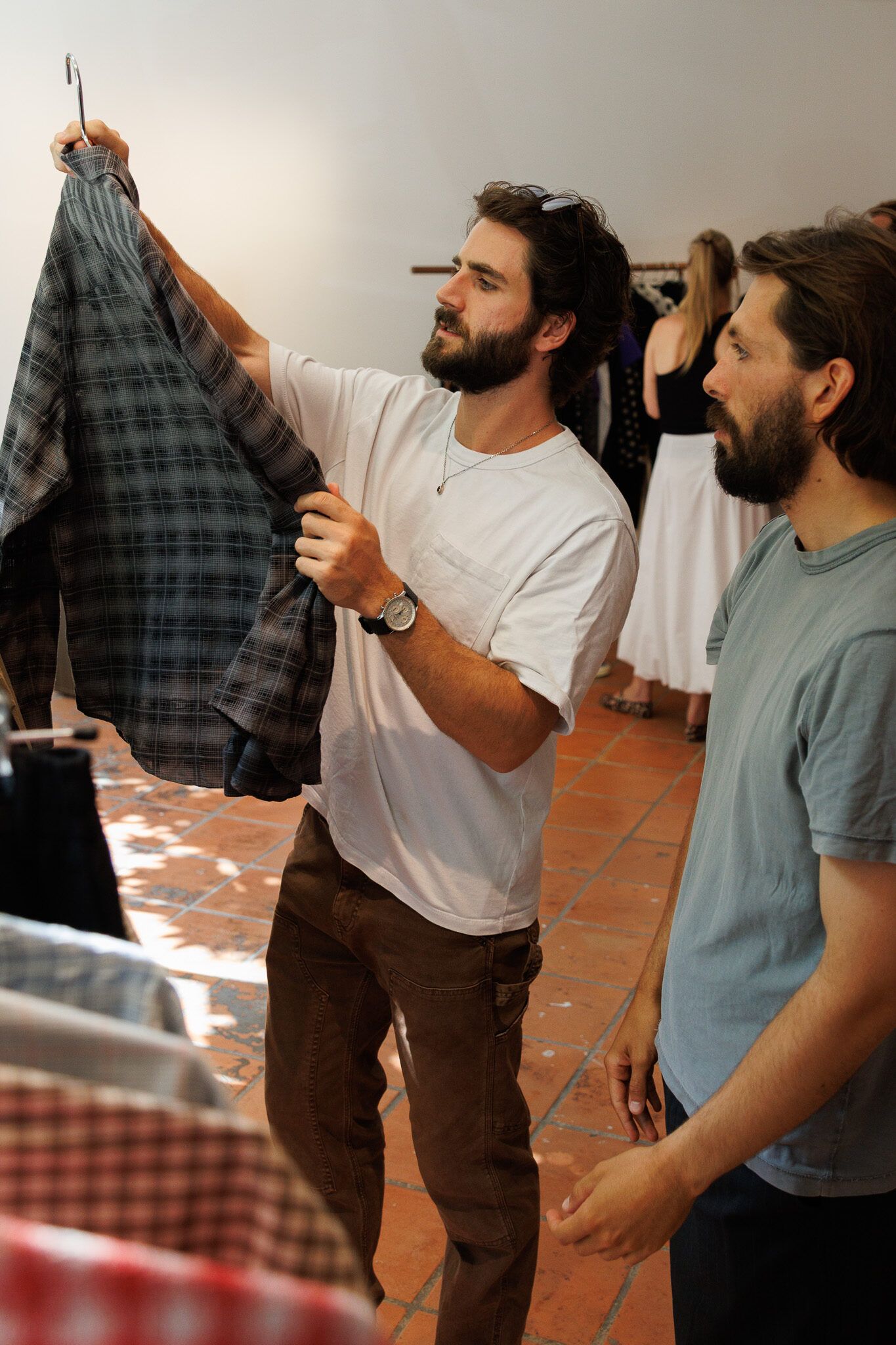 Two buyers holding up a checked shirt between the rails.