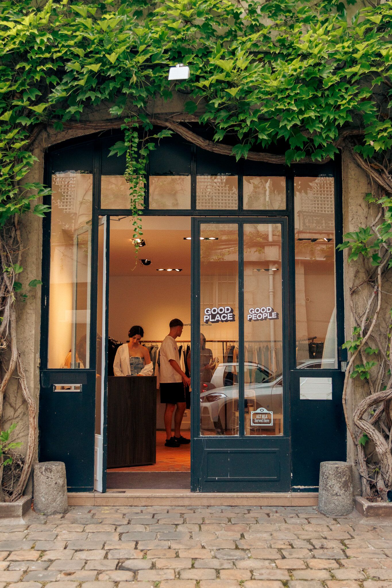 The showroom entrance under climbing ivy, the doors open onto the cobbles.
