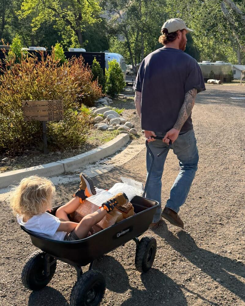 John Kiszely, founder of Good People, seen from behind pulling a cart along a gravel track.
