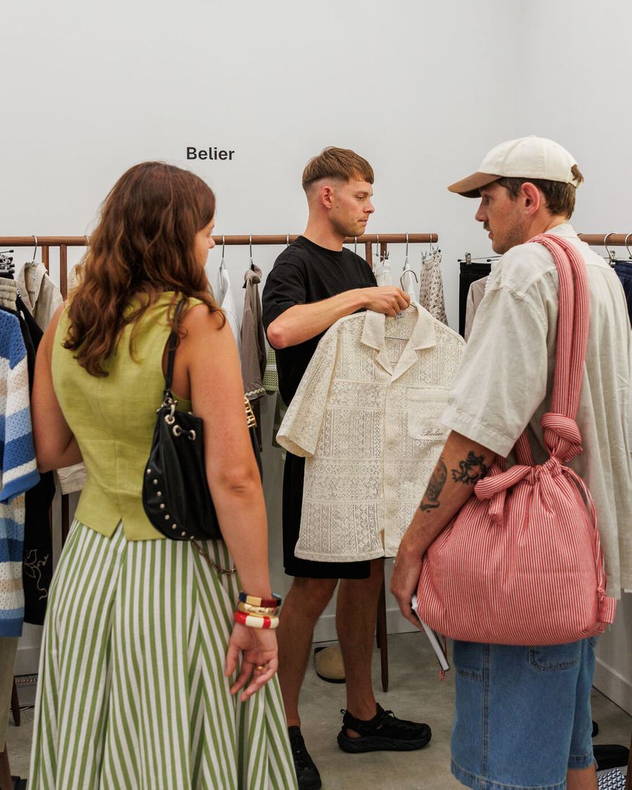 Buyers holding up a shirt beside a woman in a striped skirt.